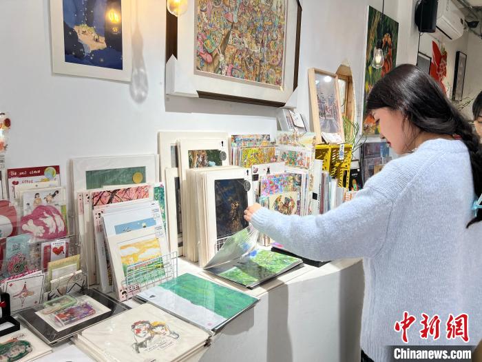 圖為藝術(shù)品商店內(nèi)，顧客挑選插畫作品。　鐘旖 攝