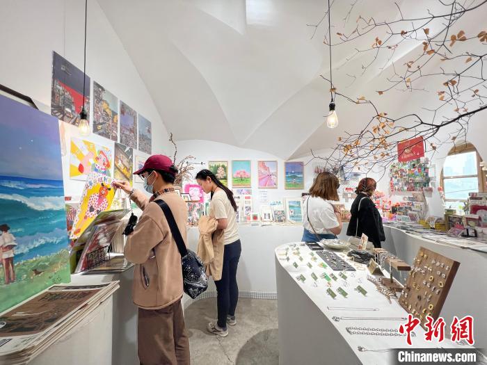 圖為藝術(shù)品商店內(nèi)，顧客挑選插畫作品?！＄婌?攝