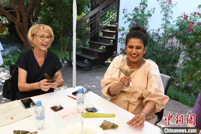 圖為嘉賓展示包粽子成果?！“亓种袊幕行墓﹫D。