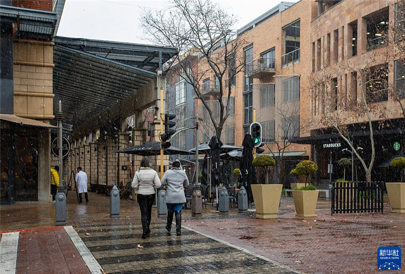 7月10日，在南非約翰內(nèi)斯堡一處商業(yè)區(qū)，人們在雪中行走。新華社記者 張譽東 攝