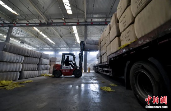 新疆喀什綜合保稅區(qū)，喀什啟路國際貿(mào)易有限公司的倉庫內(nèi)，工人正在裝載從塔吉克斯坦和烏茲別克斯坦進口的棉花。劉新攝