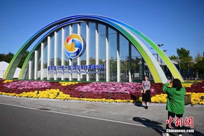 10月15日，北京，工作人員在國(guó)家會(huì)議中心外的第三屆“一帶一路”國(guó)際合作高峰論壇景觀布置前拍照留念。當(dāng)日，位于國(guó)家會(huì)議中心的第三屆“一帶一路”國(guó)際合作高峰論壇新聞中心啟動(dòng)試運(yùn)行。據(jù)悉，第三屆“一帶一路”國(guó)際合作高峰論壇將于10月17日至18日在北京舉行。<a target='_blank' href='/'><p  align=