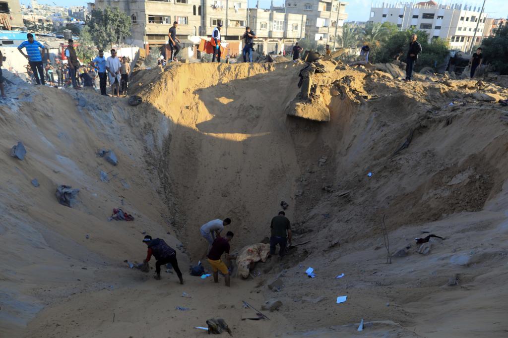 10月16日，在加沙地帶南部城市汗尤尼斯，人們在遭以色列襲擊后的建筑廢墟中救援傷者。 新華社發(fā)（亞西爾·庫迪 攝）