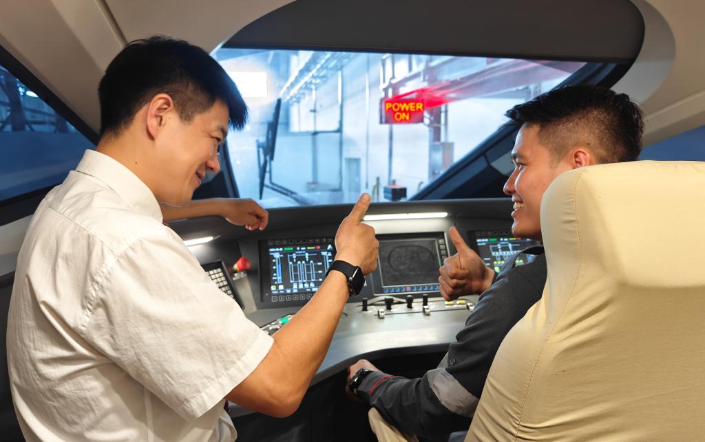 8月25日，在印度尼西亞萬隆的雅萬高鐵德卡魯爾動車所內(nèi)，中國師傅穆振（左）在向印尼火車司機(jī)塞蒂亞萬講解動車組出庫前的上電作業(yè)。