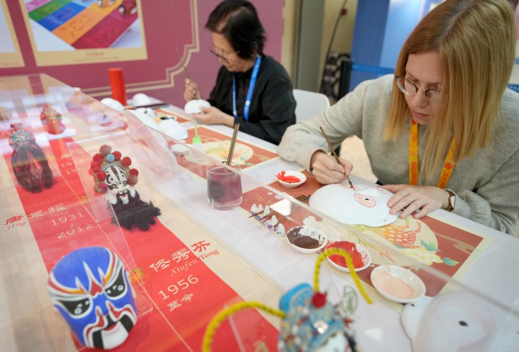 10月16日，在第三屆“一帶一路”國(guó)際合作高峰論壇新聞中心，來自比利時(shí)的記者（右）體驗(yàn)畫京劇臉譜。新華社記者 王毓國(guó) 攝