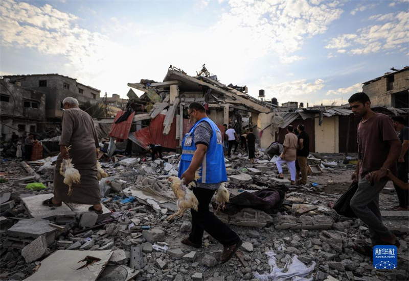10月27日，在加沙地帶南部城市汗尤尼斯，人們經(jīng)過(guò)以軍襲擊后的房屋廢墟。
