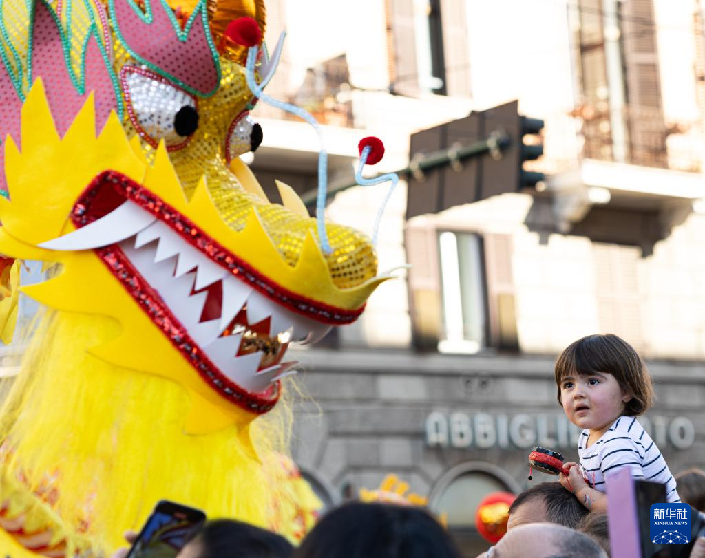 2月18日，在意大利羅馬，一名小朋友在彩妝巡游上觀看舞龍。新華社記者 李京 攝