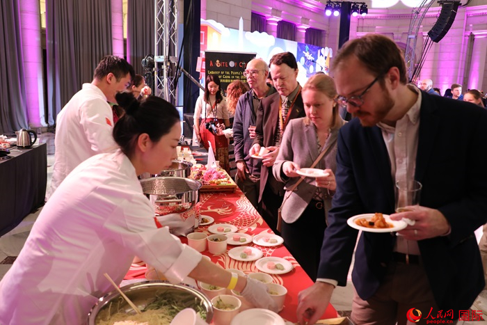 當(dāng)?shù)貢r(shí)間3月7日晚，華盛頓聯(lián)合車站廣場(chǎng)舉行駐美使團(tuán)“使館主廚挑戰(zhàn)賽”。圖為當(dāng)?shù)孛癖娫谥袊?guó)展臺(tái)前體驗(yàn)中國(guó)美食。人民網(wǎng)記者 李志偉攝