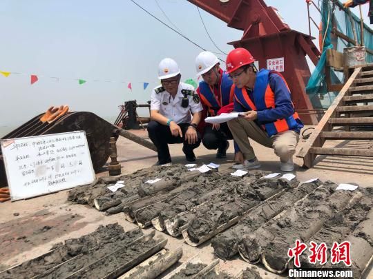 圖為勘察設(shè)計人員與海事局工作人員查看巖芯情況?！∥赫?攝
