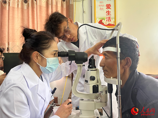 王紅英（左）和團(tuán)隊(duì)成員為達(dá)熱村村民檢查眼睛。人民網(wǎng)記者 杜燕飛攝