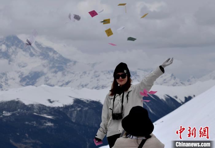 圖為5月14日，游客在西藏林芝色季拉山觀景臺拋灑“隆達(dá)”(風(fēng)馬旗，藏族民眾的一種祈福方式)?！±盍?攝