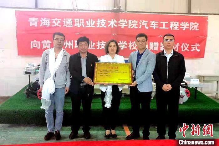 圖為李富香(中)代表學(xué)校為州縣技校捐贈器材。(資料圖) 青海省教育廳供圖