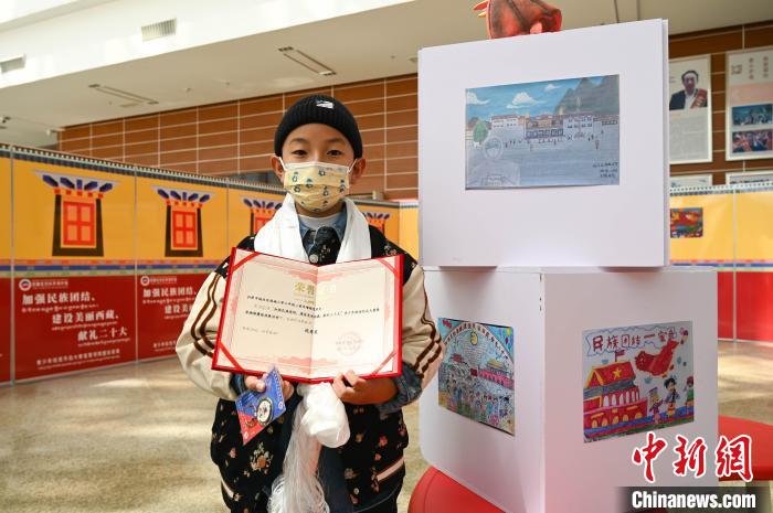 圖為一名獲獎(jiǎng)學(xué)生與自己的繪畫作品合影?！≮w朗 攝