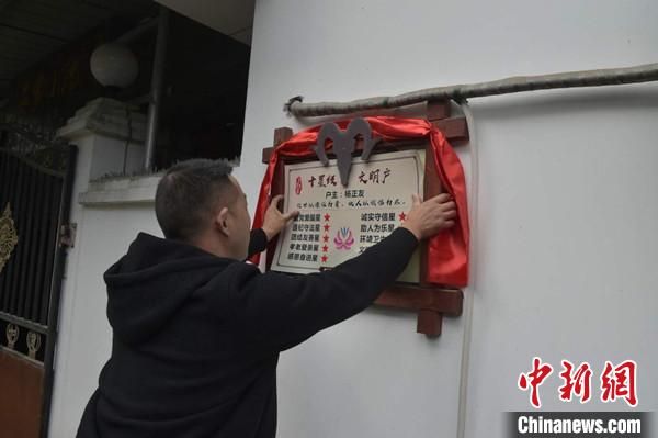 桂溪鎮(zhèn)渭溝村政府工作人員為“十星級文明戶”掛上牌匾?！钣?攝