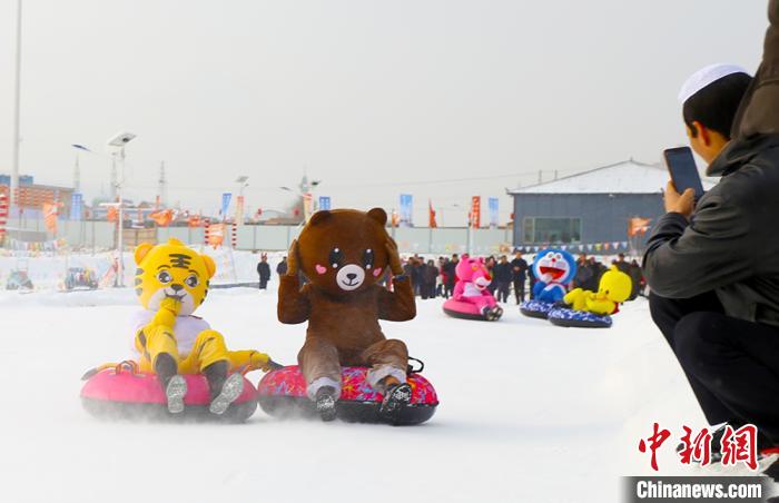 圖為臨夏市南龍鎮(zhèn)馬家莊村舉辦的鄉(xiāng)村文化旅游節(jié)上，游客穿著卡通服裝在體驗(yàn)雪上飛碟項(xiàng)目。近年來，臨夏州形成了“春賞花、夏避暑、秋摘果、冬玩雪”的全季節(jié)旅游產(chǎn)品體系。(資料圖) 高展 攝