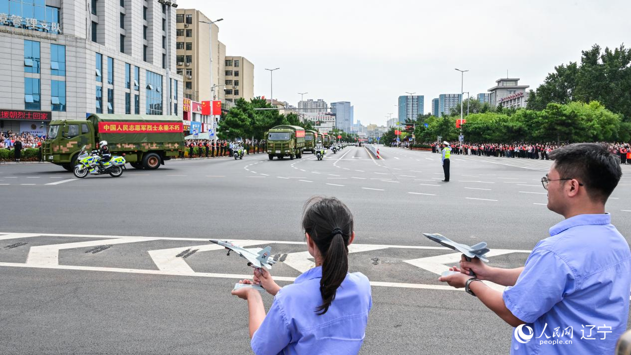 航空工業(yè)沈飛的青年技術(shù)人員拿著受閱戰(zhàn)機(jī)的模型迎接烈士遺骸。航空工業(yè)沈飛供圖