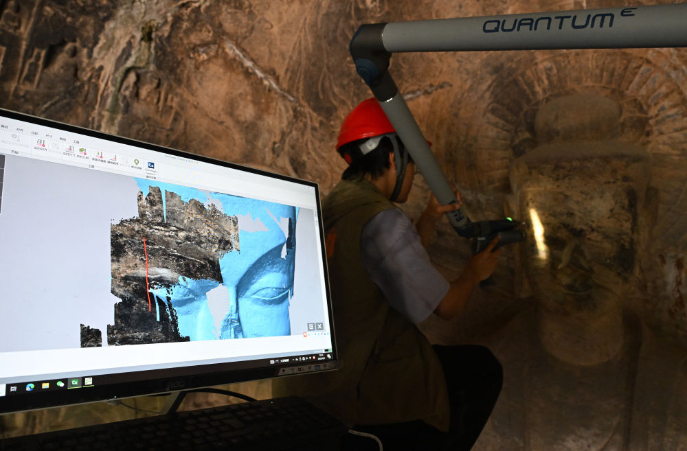 2025年4月9日，武漢大學(xué)文化遺產(chǎn)智能計(jì)算實(shí)驗(yàn)室團(tuán)隊(duì)成員在魏字洞使用關(guān)節(jié)臂掃描儀對(duì)佛像進(jìn)行數(shù)字化掃描。圖片來源新華社