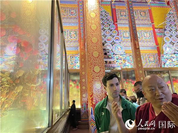 7月25日，省級(jí)非物質(zhì)文化遺產(chǎn)項(xiàng)目塔爾寺酥油花的代表性傳承人朋措堅(jiān)參（右）在塔爾寺酥油花館講解酥油花的制作過(guò)程。人民網(wǎng) 謝瑩攝