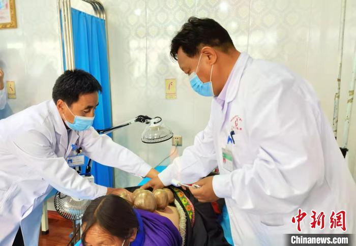 圖為看照加手把手帶徒弟加老(左一)進(jìn)行拔罐療法。　張婧 攝