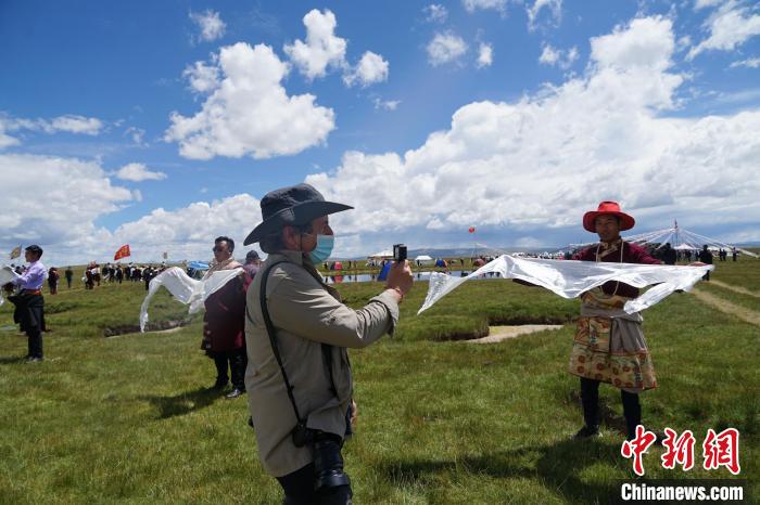 圖為一名外籍?dāng)z影師記錄當(dāng)?shù)夭刈鍤g迎儀式。　馬銘言 攝