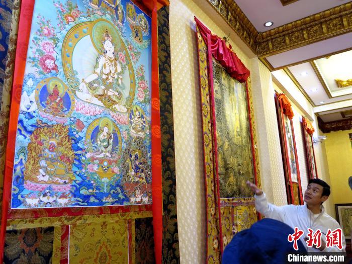 圖為完德尖措展示熱貢龍樹畫苑內(nèi)的唐卡。　張?zhí)砀?攝
