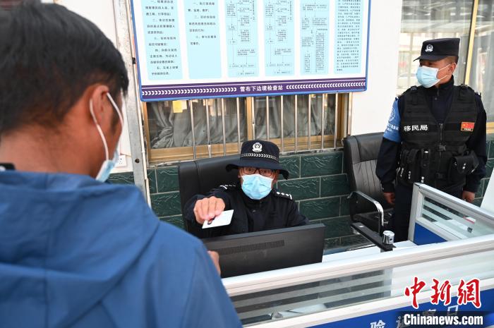 圖為移民管理警察登記完身份信息后將證件歸還給行人?！≮w朗 攝