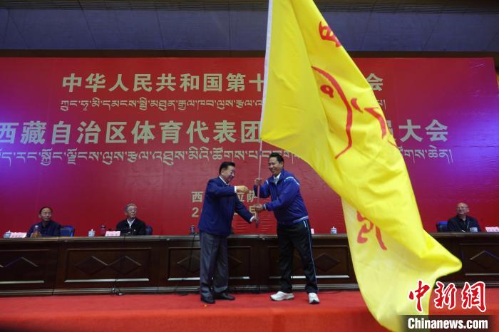 西藏自治區(qū)副主席甲熱·洛桑丹增授代表團團旗，西藏自治區(qū)體育局局長尼瑪次仁接旗?！∪轿木?攝