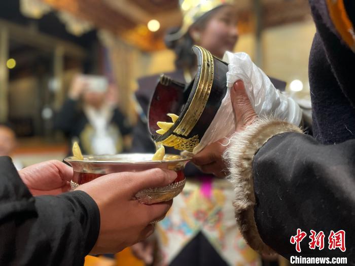 圖為主人在碗中斟滿青稞酒。　冉文娟 攝