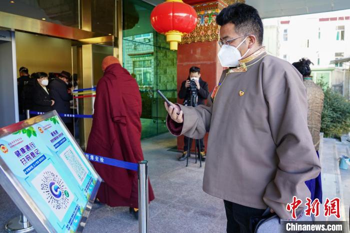 圖為政協(xié)委員掃場所碼進入會場?！〗w波 攝