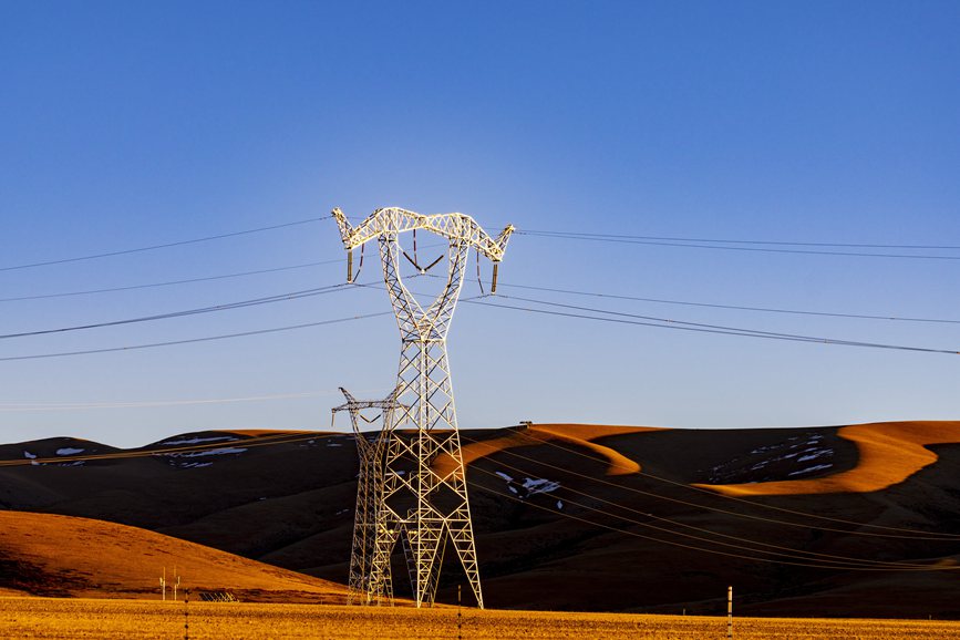 阿里地區(qū)的曠野上，電力鐵塔在夕陽(yáng)下熠熠生輝。