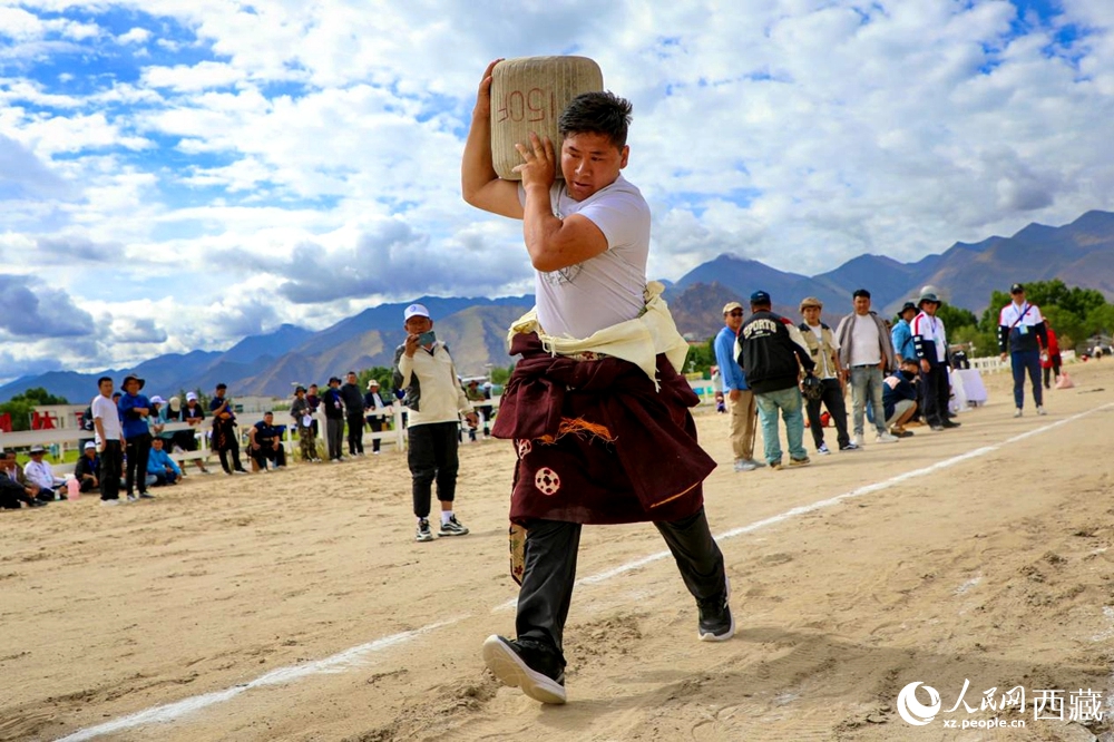 來自拉薩市當(dāng)雄縣的牧民選手將一塊150斤重的石頭扛在肩上飛奔。