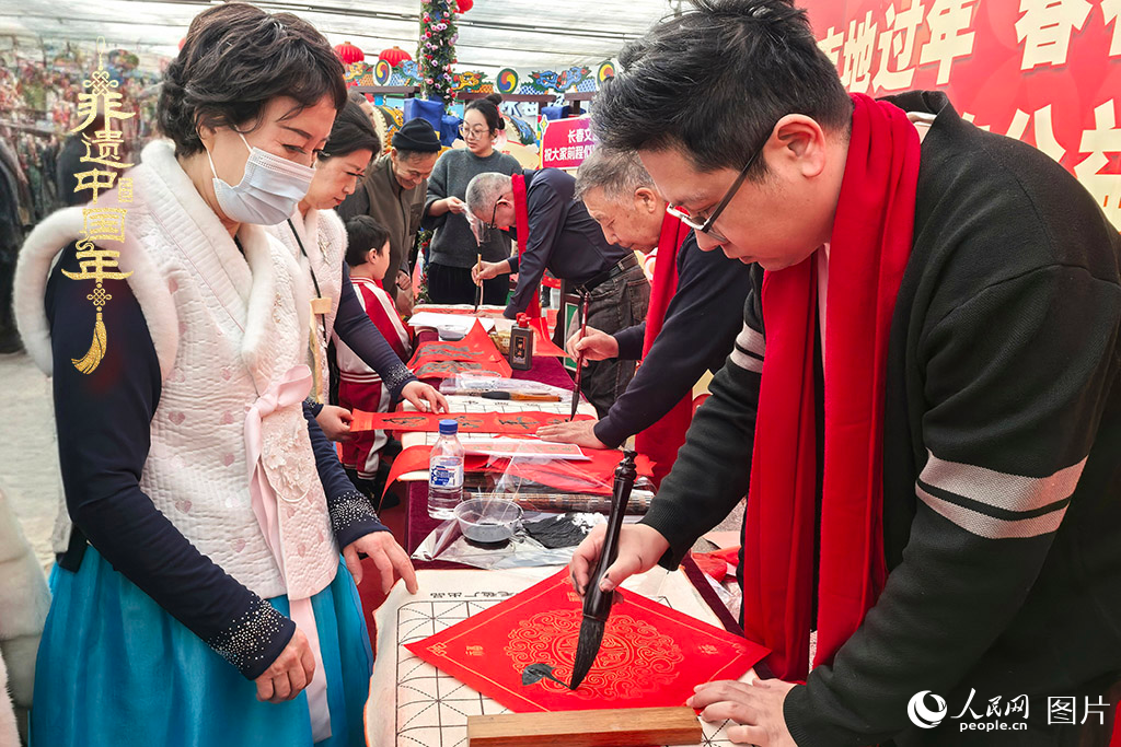 新春佳節(jié)之際，長春農(nóng)博園冬季展會(huì)火熱進(jìn)行，展廳內(nèi)，書法家現(xiàn)場(chǎng)書寫“?！弊郑忻裼慰图娂娚锨坝航印案！?。人民網(wǎng)記者 王海躍攝